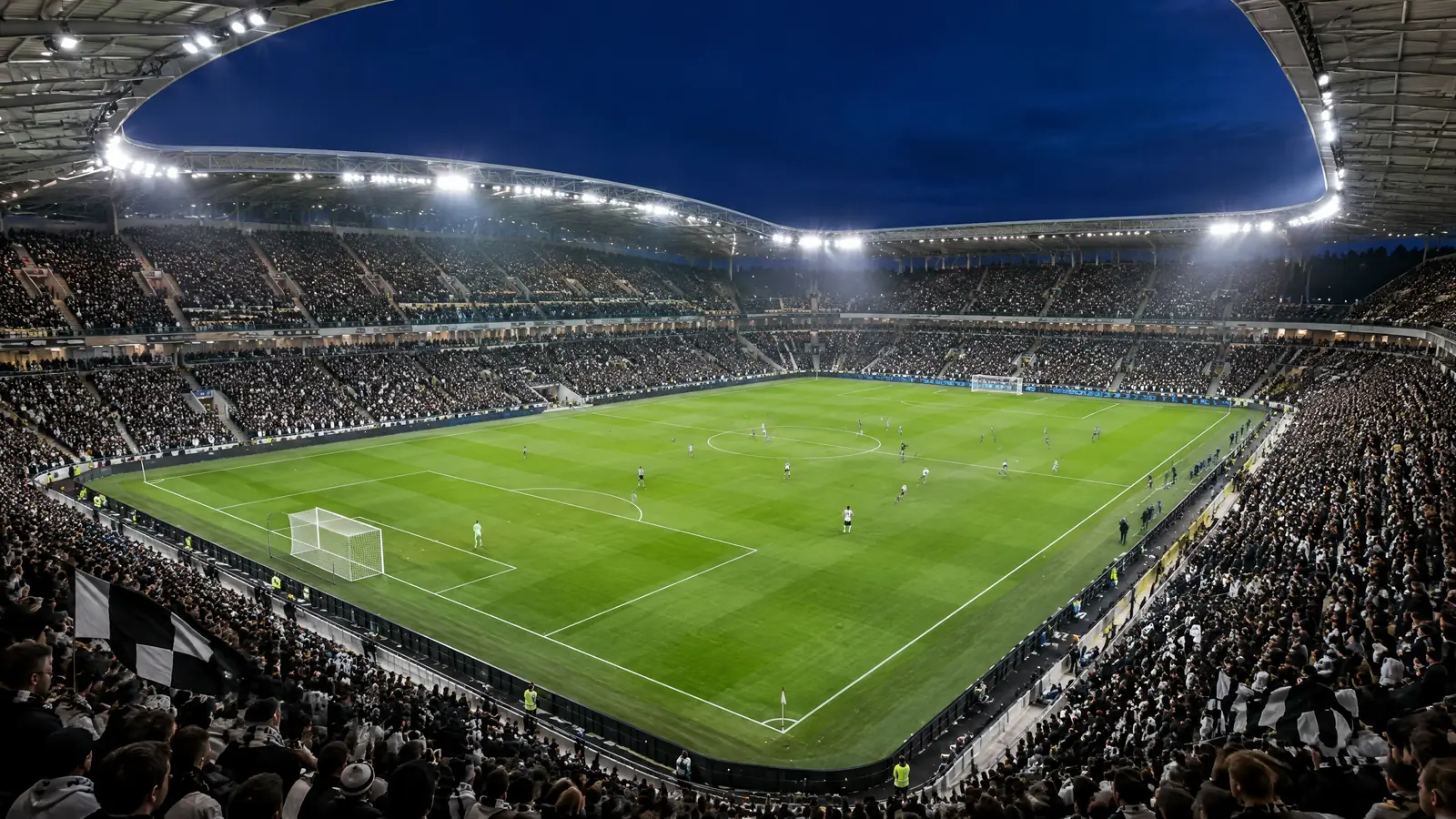 Modern single-club football stadium under floodlights during an evening match